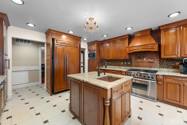 kitchen featuring sink, a kitchen island with sink, built in appliances, light stone counters, and custom exhaust hood