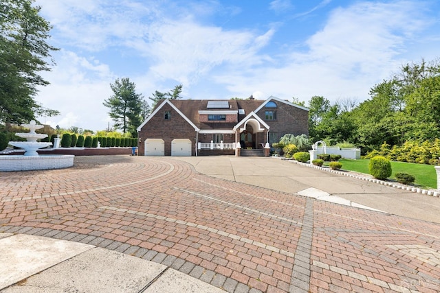 view of front of property featuring brick siding, solar panels, fence, decorative driveway, and a garage