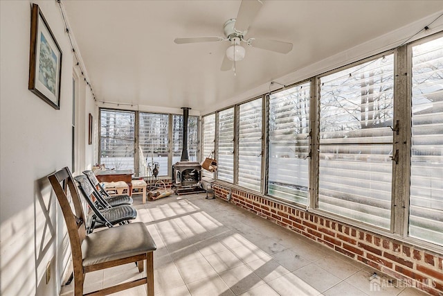 sunroom with a wood stove and ceiling fan