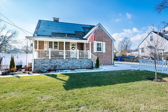 view of front of property with a front lawn, covered porch, and solar panels