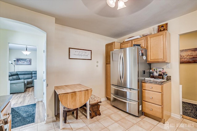 kitchen featuring light tile patterned floors, stainless steel fridge, ceiling fan, hanging light fixtures, and light brown cabinets