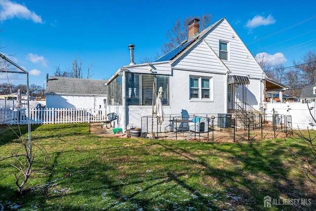 back of property with central AC unit and a yard