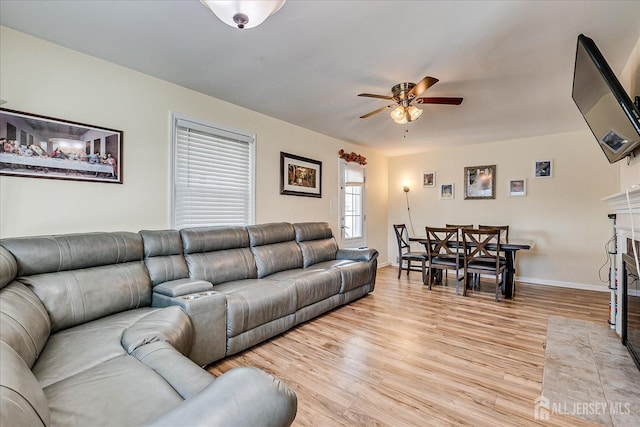 living room with a fireplace, light hardwood / wood-style flooring, and ceiling fan