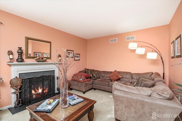 living room with a fireplace with flush hearth, visible vents, baseboards, and light colored carpet