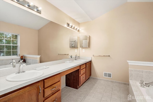 bathroom with a garden tub, double vanity, a sink, and visible vents