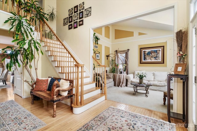 interior space with high vaulted ceiling, stairway, and wood finished floors