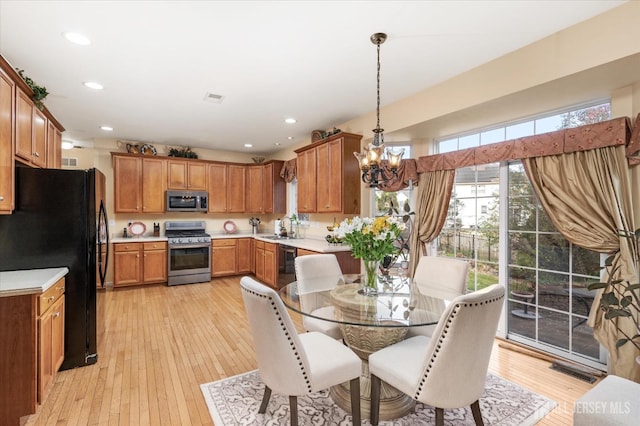 kitchen with appliances with stainless steel finishes, light countertops, a sink, and pendant lighting