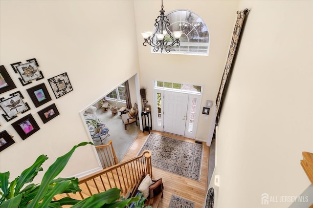 foyer featuring an inviting chandelier, a high ceiling, and wood finished floors