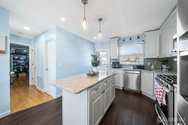 kitchen featuring sink, appliances with stainless steel finishes, hanging light fixtures, a center island, and white cabinets