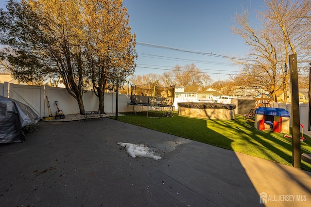 view of yard featuring a trampoline, a swimming pool, and a patio area