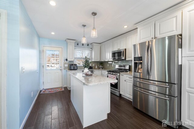 kitchen featuring white cabinetry, stainless steel appliances, light stone countertops, and hanging light fixtures