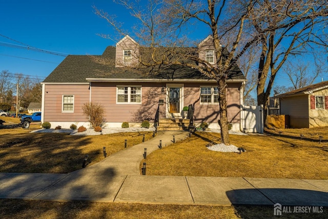 cape cod house with roof with shingles and a front yard