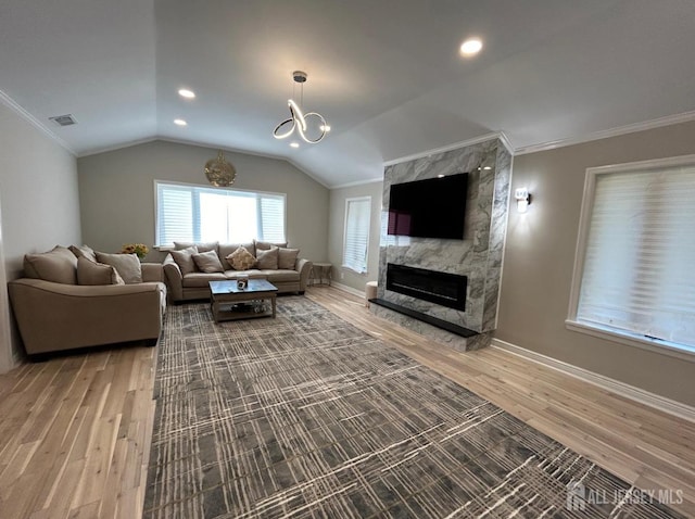 living room featuring a premium fireplace, crown molding, vaulted ceiling, and hardwood / wood-style flooring