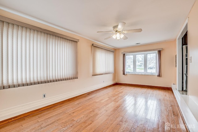 empty room with a ceiling fan, light wood finished floors, and baseboards