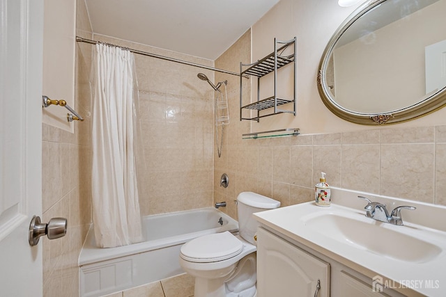 bathroom with tile walls, toilet, shower / bath combo with shower curtain, vanity, and tile patterned floors