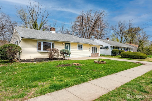 ranch-style house with a front yard, a chimney, a patio, and roof with shingles