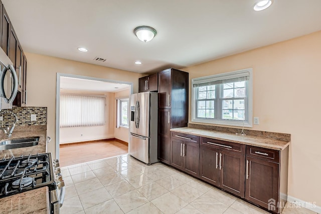 174 Winthrop Rd, Edison, NJ 08817 - kitchen with stainless steel appliances, dark brown cabinetry, light tile patterned floors, light stone countertops, and tasteful backsplash