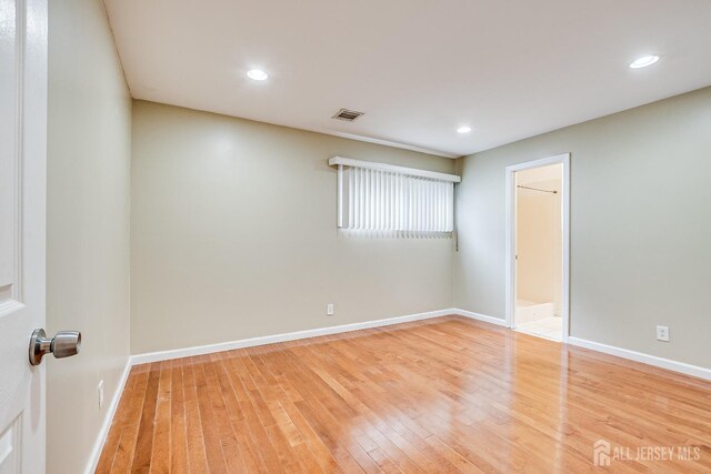 empty room with wood finished floors, baseboards, and recessed lighting