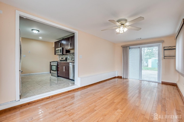 unfurnished room with baseboards, a ceiling fan, and light wood-style flooring