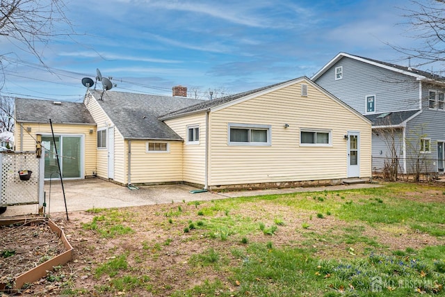 back of property with a chimney, a vegetable garden, fence, a shingled roof, and a patio
