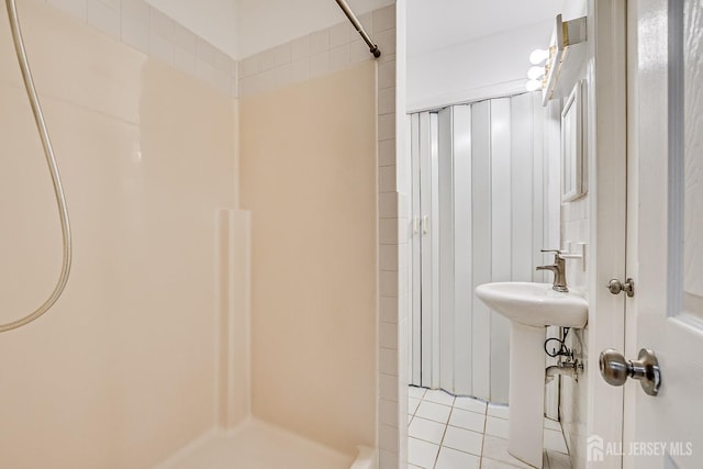 full bath featuring a shower, tile patterned floors, and a sink