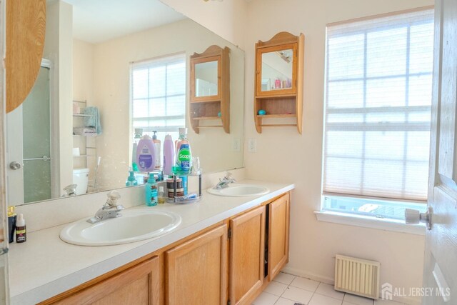 bathroom featuring vanity, radiator, tile patterned floors, and toilet