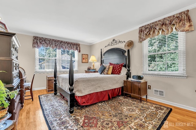 bedroom featuring multiple windows, hardwood / wood-style floors, and crown molding