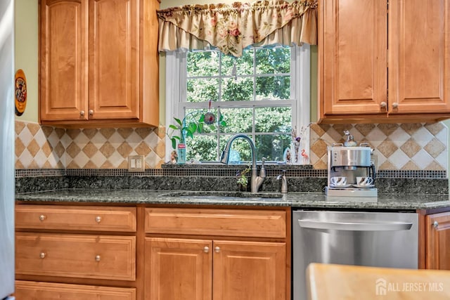 kitchen with tasteful backsplash, dark stone countertops, sink, and stainless steel dishwasher