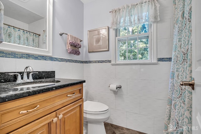 bathroom featuring vanity, tile walls, and toilet