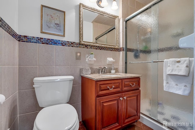 bathroom with tile walls, vanity, and a shower with shower door