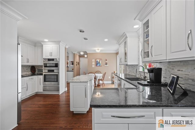 kitchen with a sink, white cabinetry, recessed lighting, backsplash, and ornamental molding