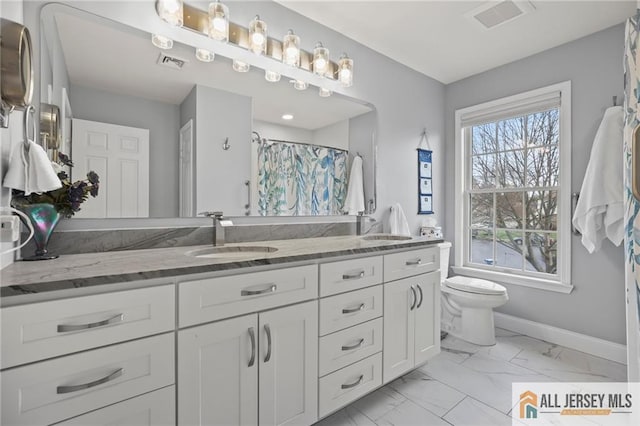 bathroom featuring marble finish floors, toilet, double vanity, curtained shower, and baseboards