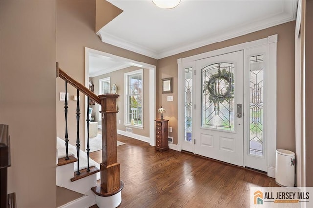 foyer featuring plenty of natural light, crown molding, wood finished floors, stairway, and baseboards