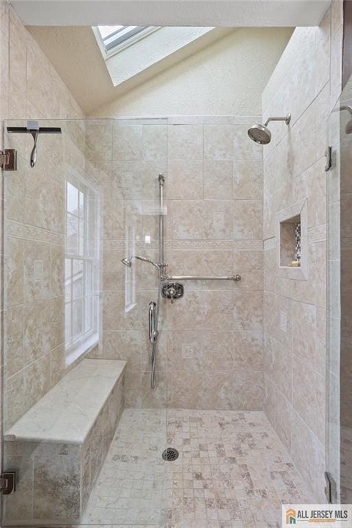 full bath with a shower stall, lofted ceiling, and a skylight