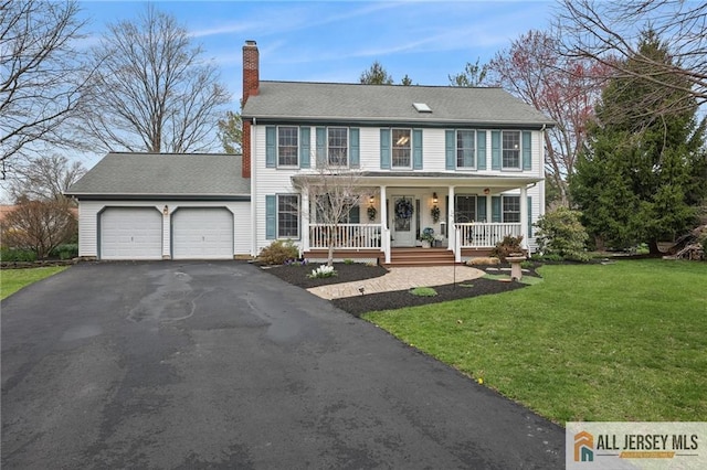 colonial-style house with a porch, a garage, driveway, a front lawn, and a chimney