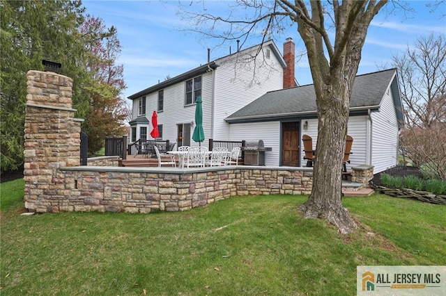 rear view of house with a chimney, a yard, and a patio area