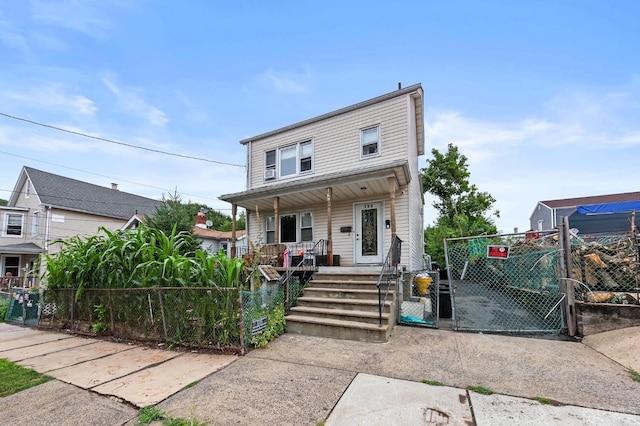 view of front of property with covered porch, a fenced front yard, and a gate