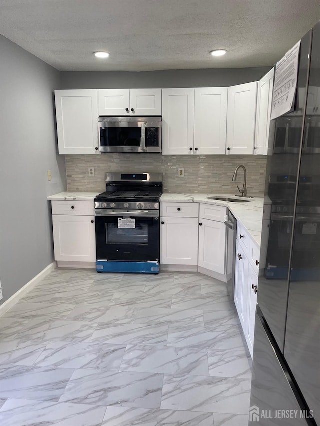 kitchen with stainless steel appliances, sink, white cabinets, and decorative backsplash