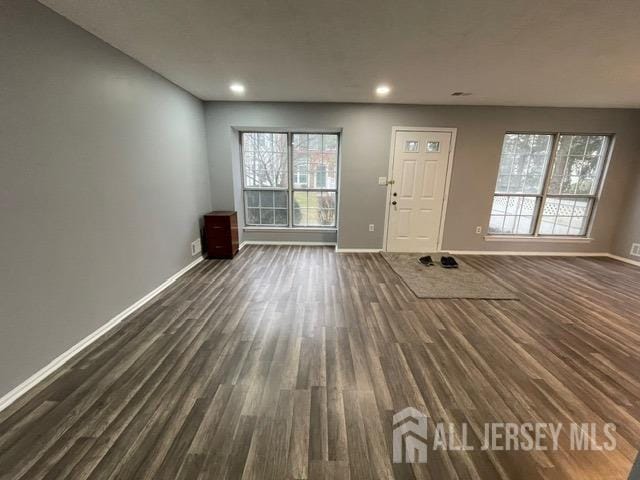 unfurnished living room featuring plenty of natural light and dark hardwood / wood-style floors