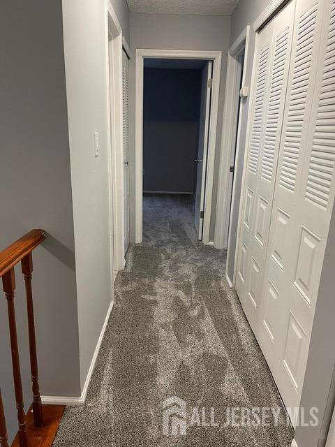 hallway with dark colored carpet and a textured ceiling