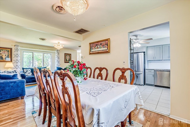 dining space with ceiling fan, light wood-style flooring, and a chandelier