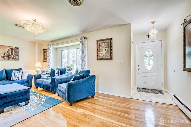 entrance foyer featuring a baseboard heating unit, plenty of natural light, light wood-style flooring, and baseboards
