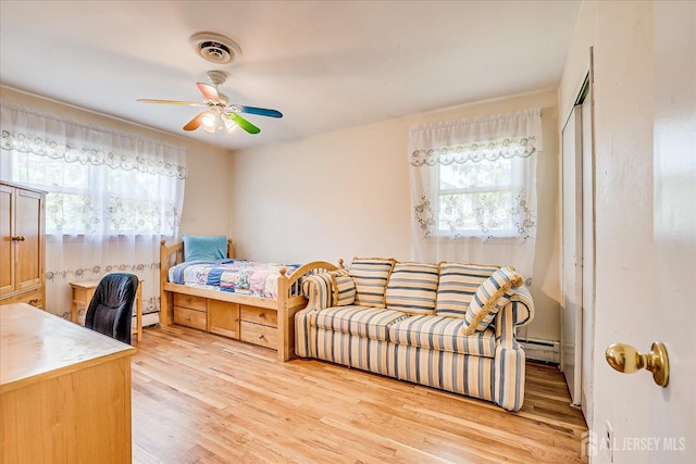 bedroom with a baseboard heating unit, light wood-type flooring, a closet, and ceiling fan