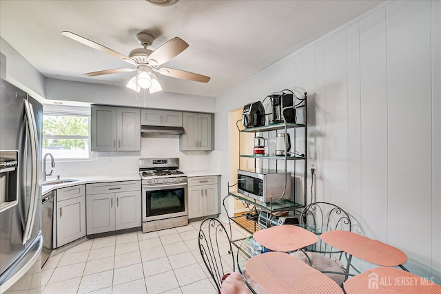 kitchen featuring gray cabinetry, stainless steel appliances, a sink, and light countertops
