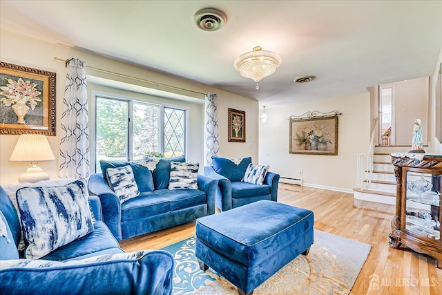 living room featuring light wood-style flooring, baseboard heating, stairway, and baseboards