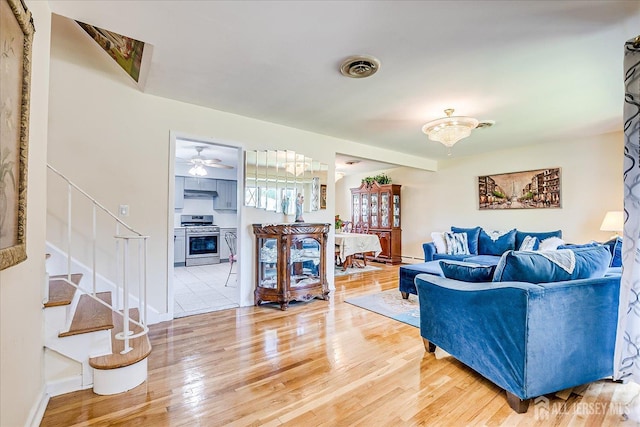 living room with wood finished floors, stairway, a chandelier, ceiling fan, and baseboards