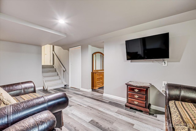 living area with wood finished floors, baseboards, and stairway