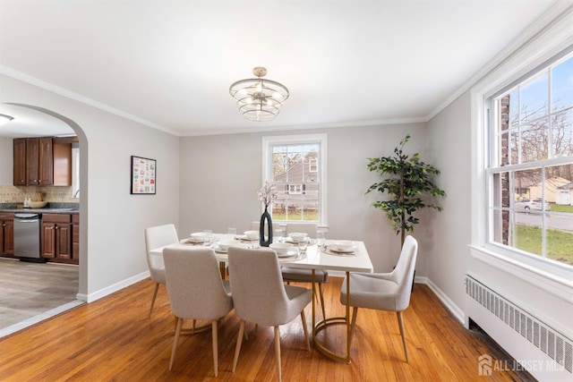334 Hillcrest Ave, Plainfield, NJ 07062 - dining area featuring radiator, arched walkways, crown molding, healthy amount of natural light, and light wood-style floors