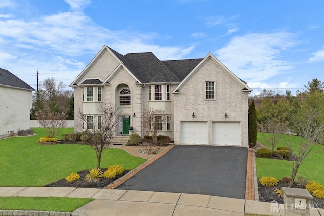 view of front facade featuring driveway, brick siding, an attached garage, and a front yard