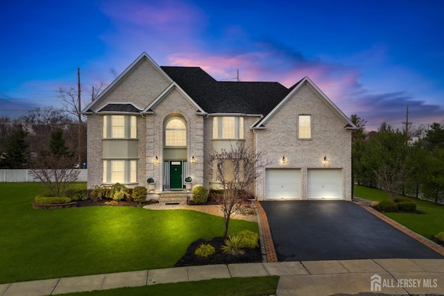 traditional home with aphalt driveway, brick siding, a yard, and a garage